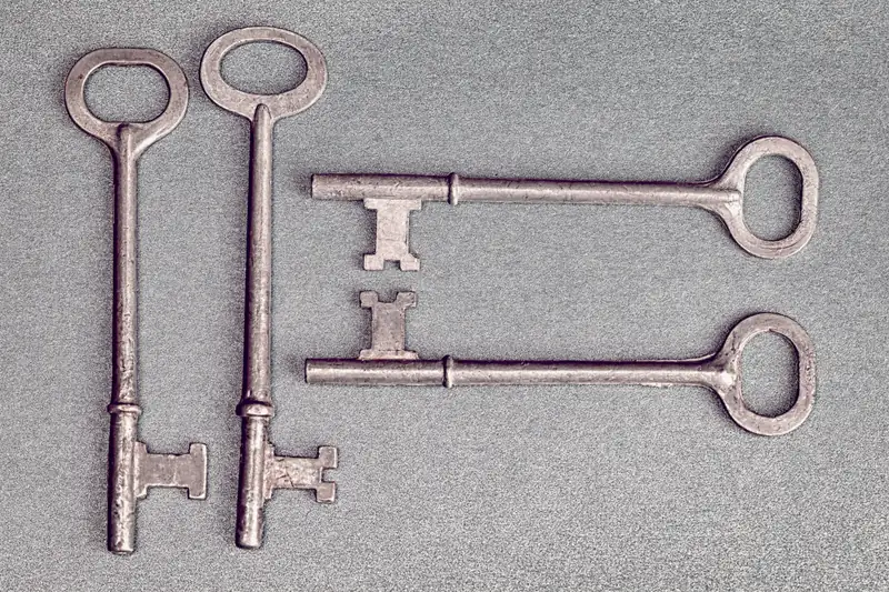Four antique skeleton keys laid out on a blue-grey background